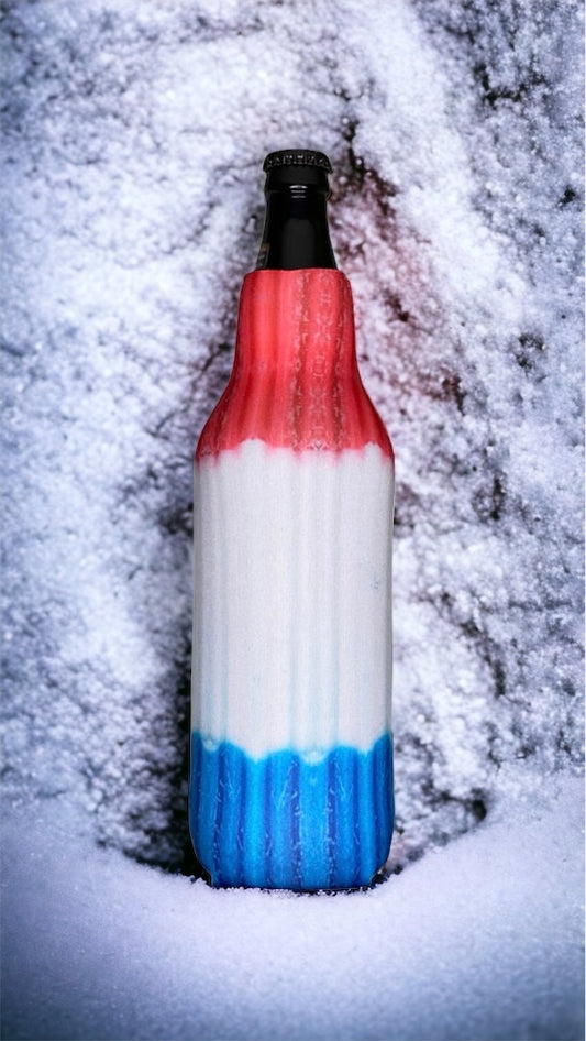 A ribbed glass bottle with a red, white, and blue horizontal striped design, standing upright in a snowy outdoor setting.