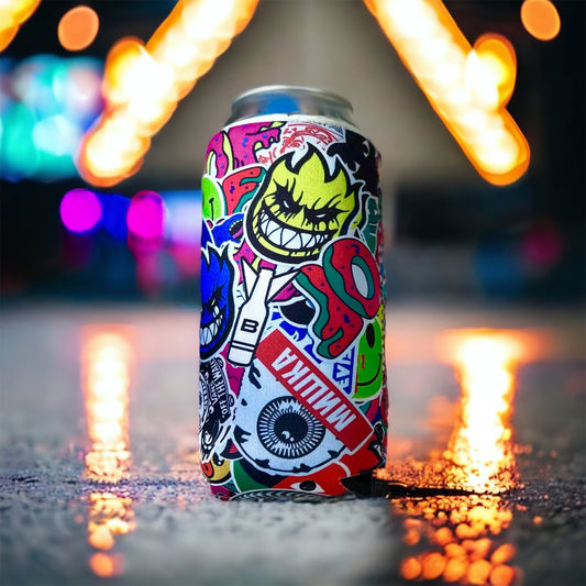 A slim aluminum can covered in a colorful graffiti-style sticker print, standing on wet pavement at night with blurred neon lights in the background.